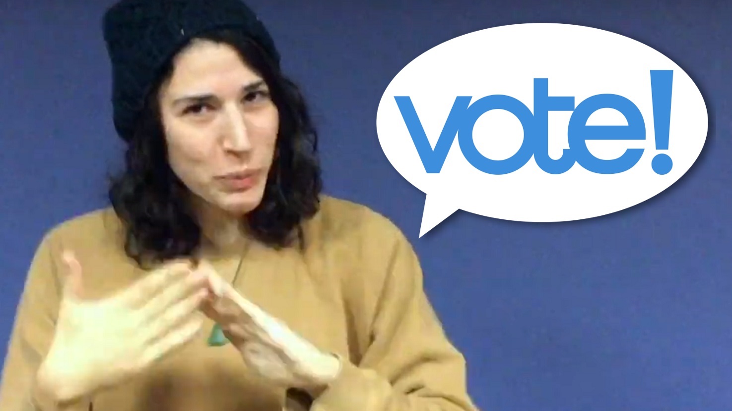 A thumbnail for a video. On the left, a light-skinned feminine-presenting person is signing the ASL word "community". On the right is a speech bubble that says "vote!".